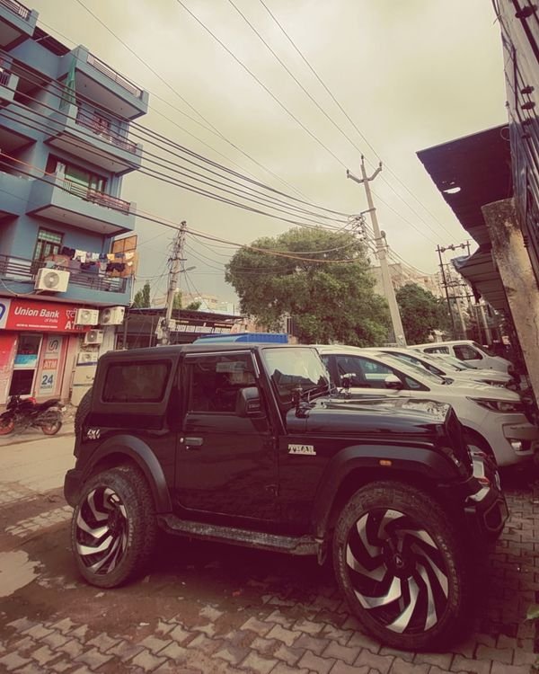 Wide-angle shot of the black Thar on a brick-paved lane under overhead wires